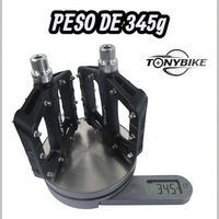 Pedales de nylon TONYBIKESGDL negros para bicicleta de montaña con pines metálicos sobre una báscula digital