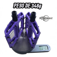 Pedales de plataforma morados TONYBIKESGDL para BMX y MTB con pines de agarre, pesando 348 gramos en báscula digital.